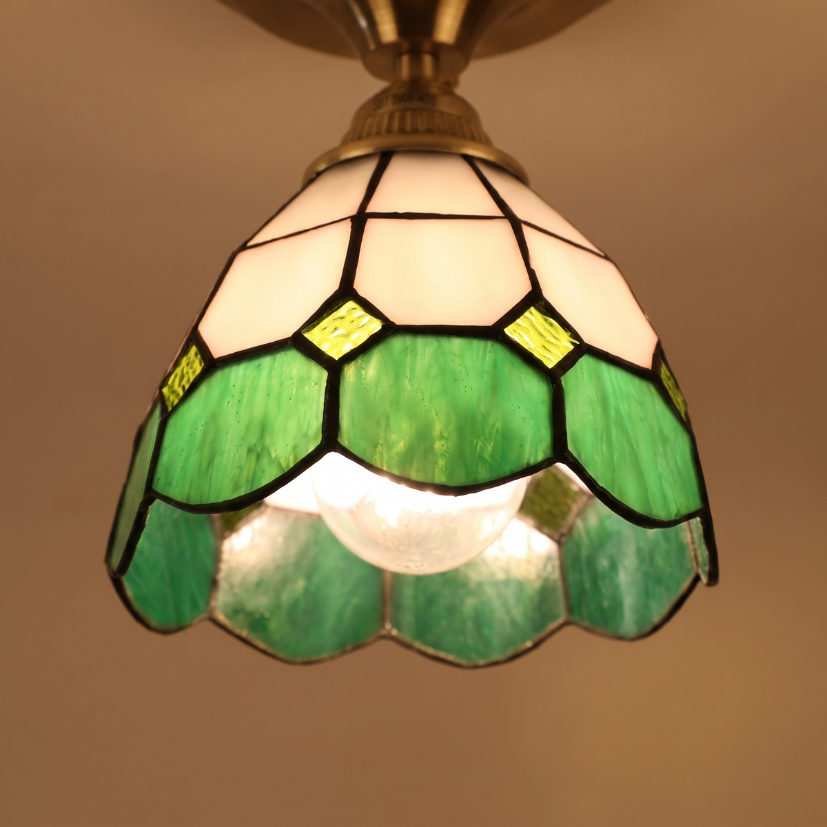 Close up of a lit Theberton shade showing the white and green leaded glass and small glass jewels