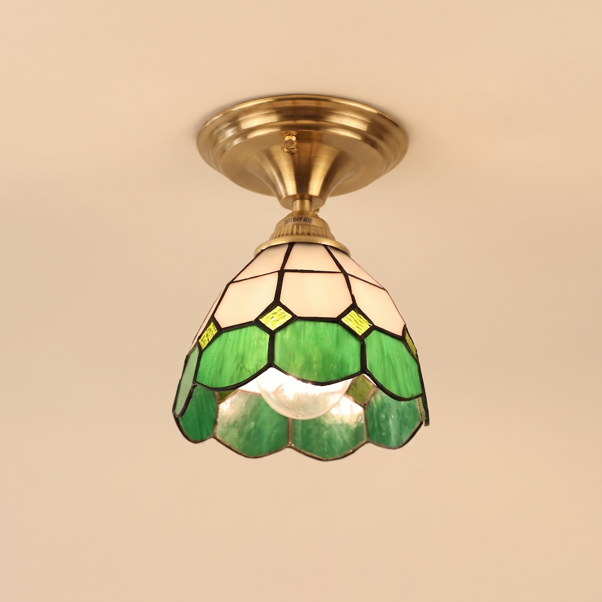 Theberton stained glass ceiling light with white and green leaded glass and a scalloped rim on an antique brass canopy, cream background