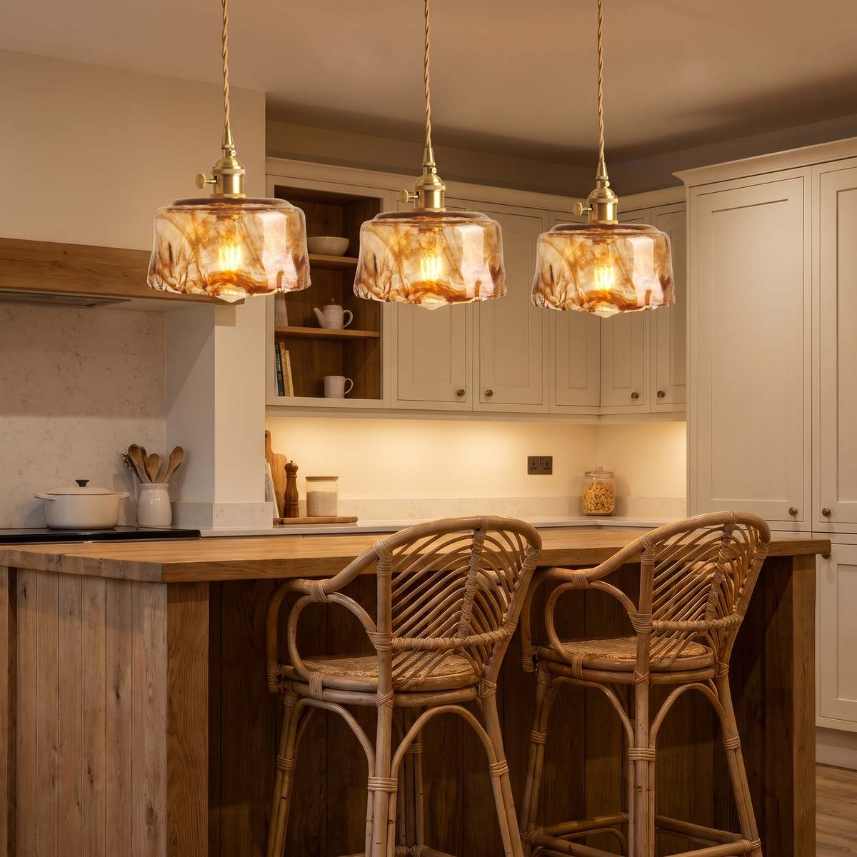 Three Walpole marbled amber glass pendants lit in a row over a kitchen island