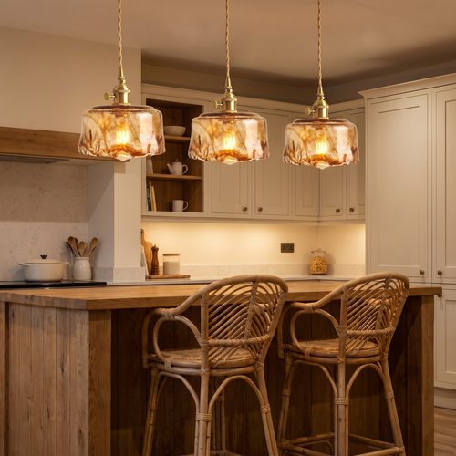 Three Walpole marbled amber glass pendants lit in a row over a kitchen island