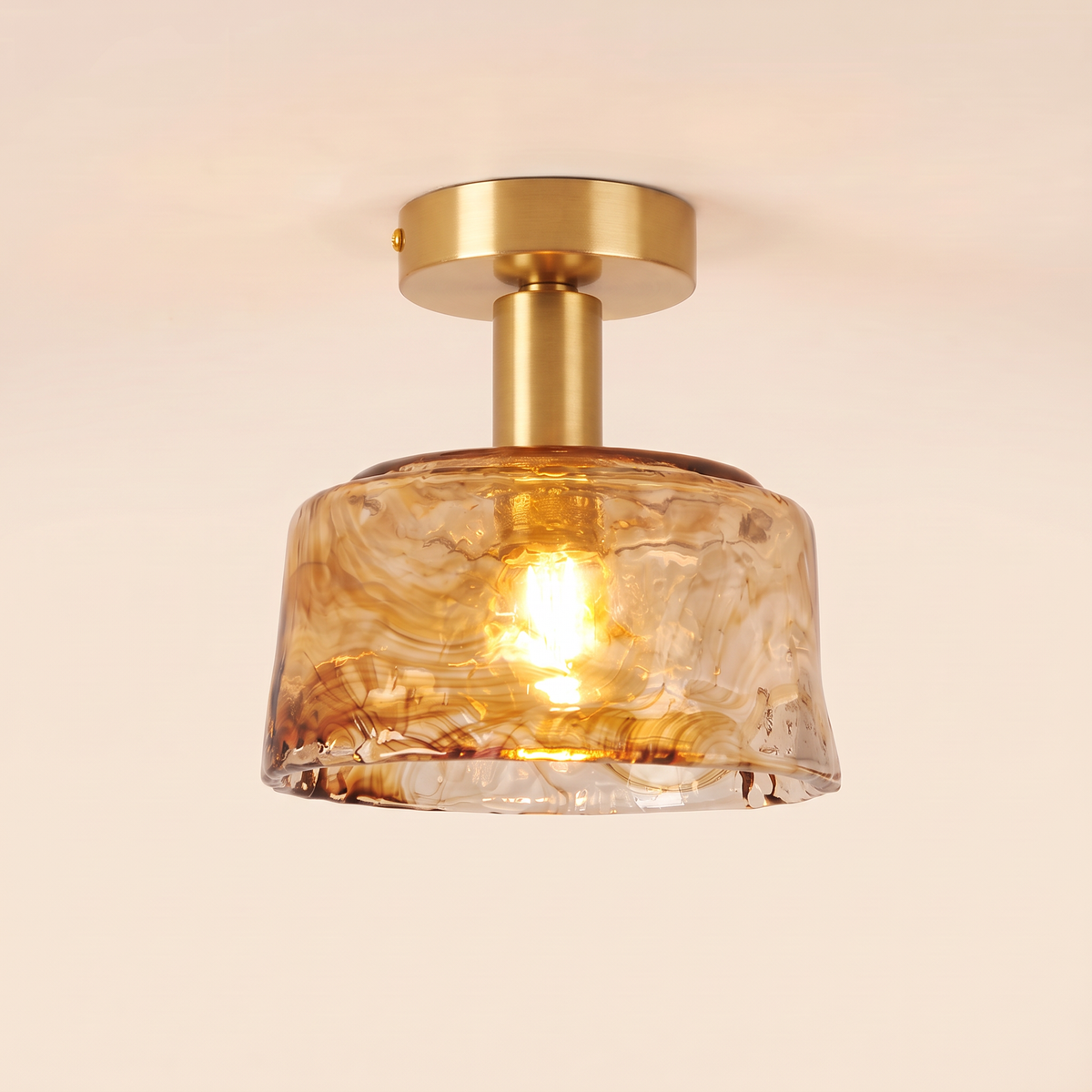 Walpole semi flush ceiling light with a marbled amber glass drum on a short brass fitting, cream background