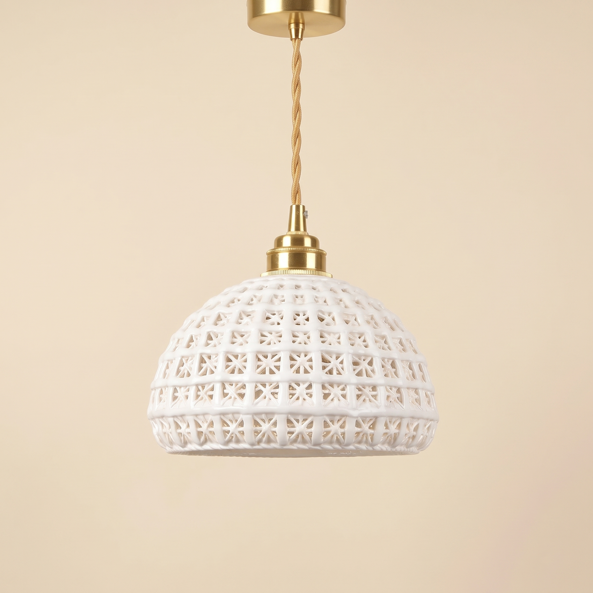Wangford pendant light with a white ceramic basket weave dome on a brass finish holder and twisted gold cord, cream background