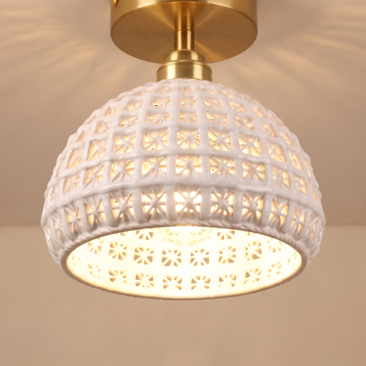 Close up of a lit Wangford ceiling light showing the ceramic basket weave and star shaped cut outs