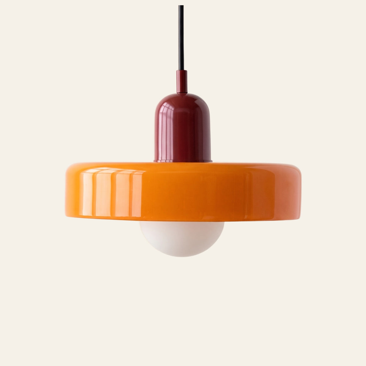 Welwyn mid century glass pendant light, orange glass disc with a burgundy cap, on a cream background
