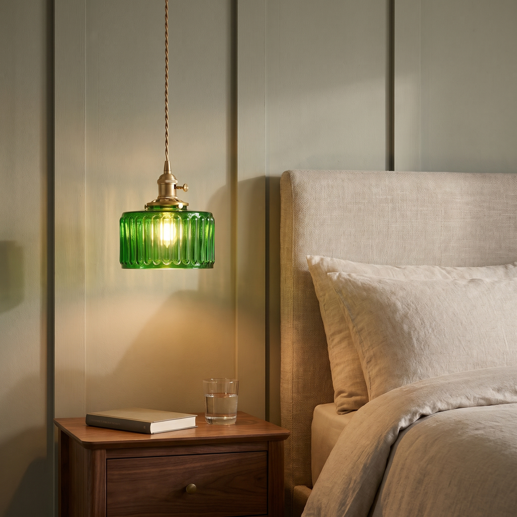 Green Wenhaston pendant hung low beside a bed over a walnut bedside table