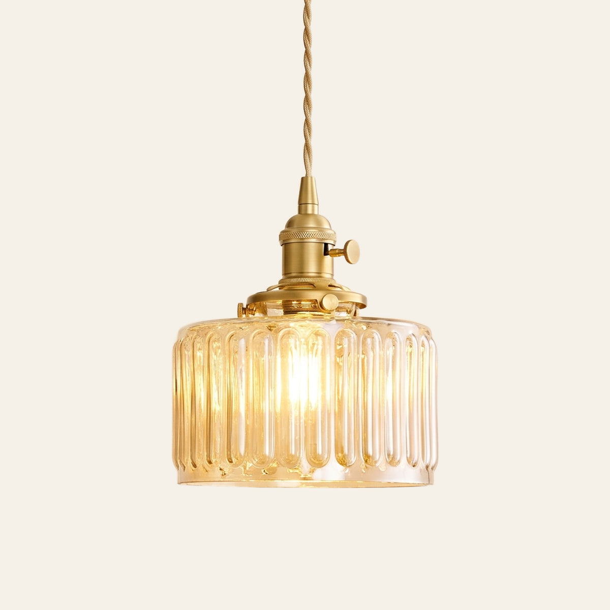 Wenhaston ribbed glass pendant light in amber with a brass switch holder and twisted cord, cream background