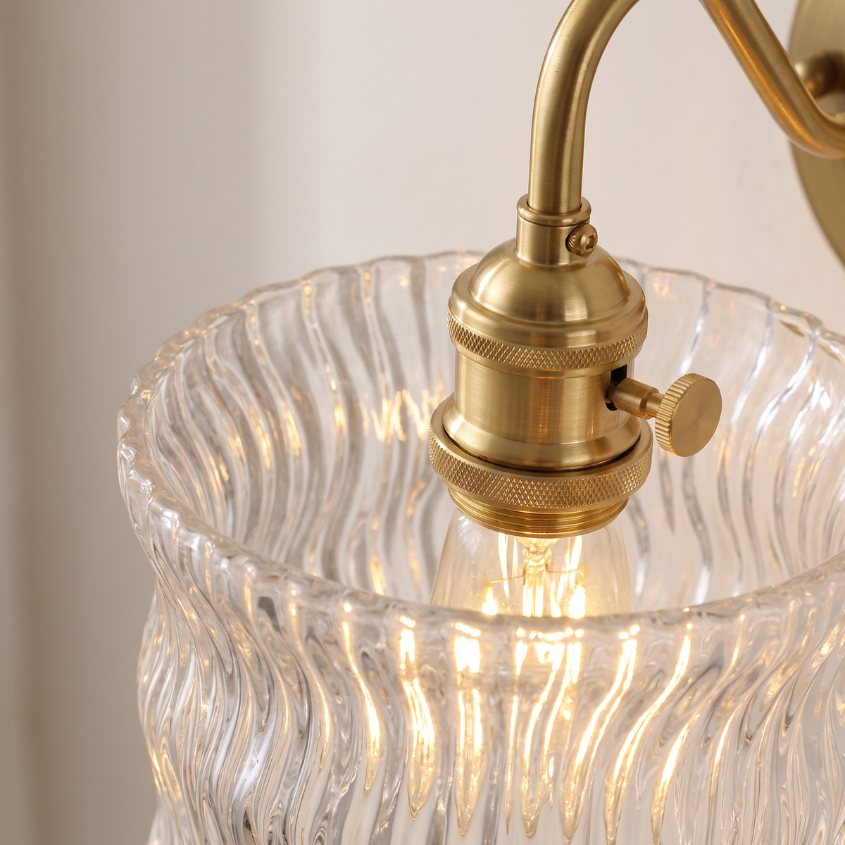 Close up of the Westleton clear rippled glass drum shade, brass holder and turn knob switch