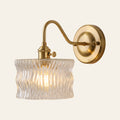 Westleton wall light with a clear rippled glass drum shade on a brass swan neck arm, lit