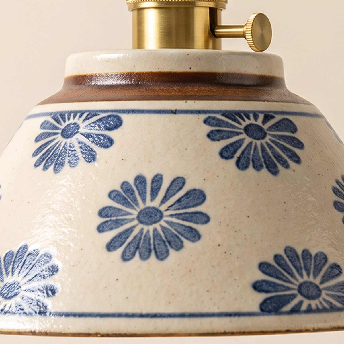Close up of the blue daisies painted on the speckled cream glaze of the Wilby shade and its brass holder