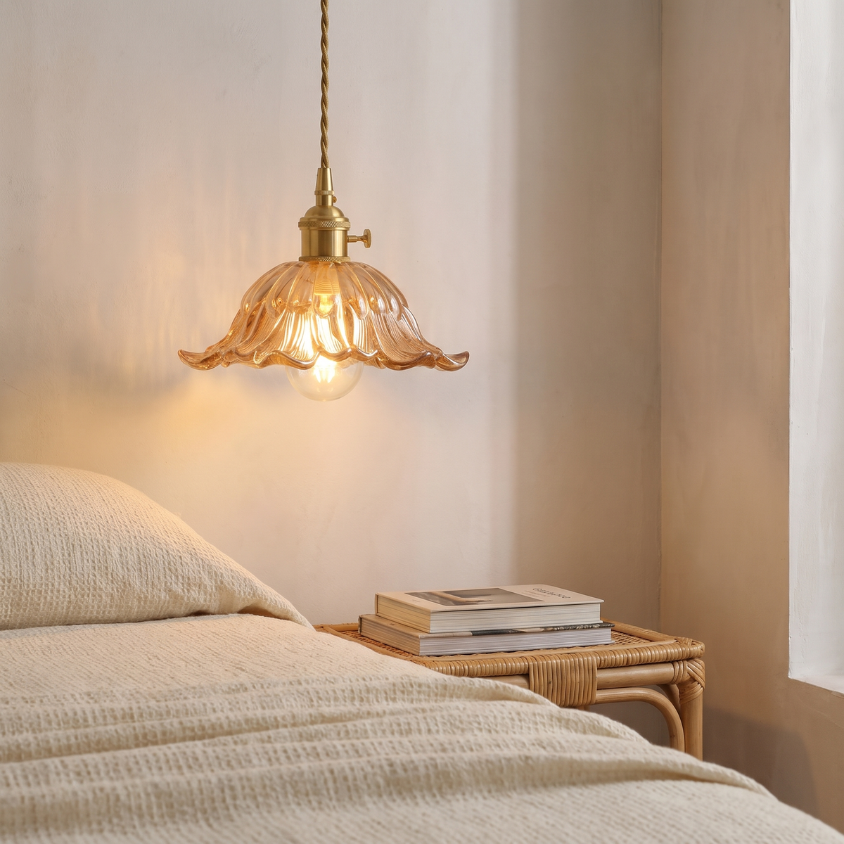 Amber Wissett flower pendant glowing beside a bed with a rattan bedside table