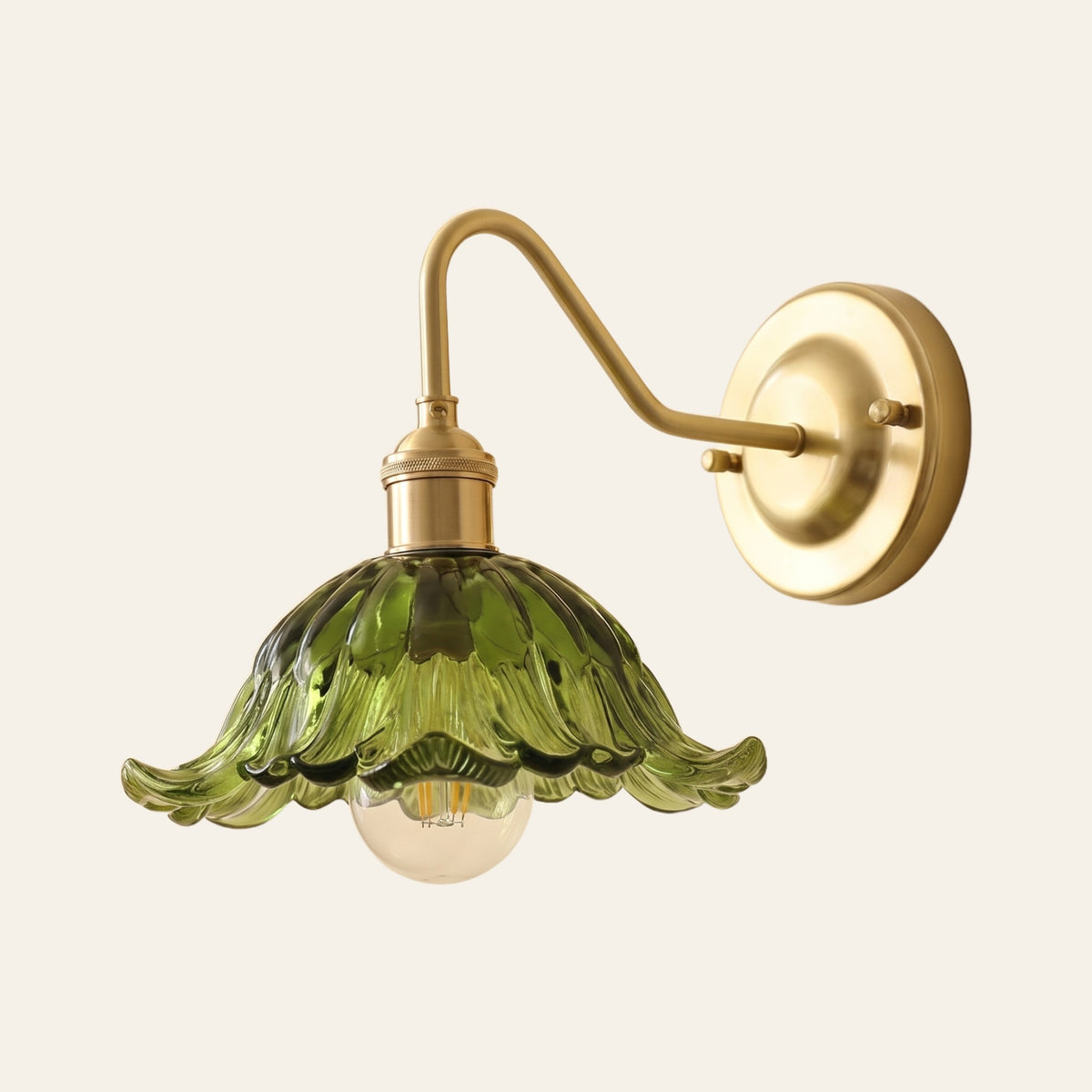 Wissett wall light with a green flower glass shade, ruffled petal rim and globe bulb on a brass swan neck arm, cream background