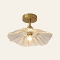 Woodbridge flush ceiling light with a wide clear fluted glass saucer shade on a brass rod, lit