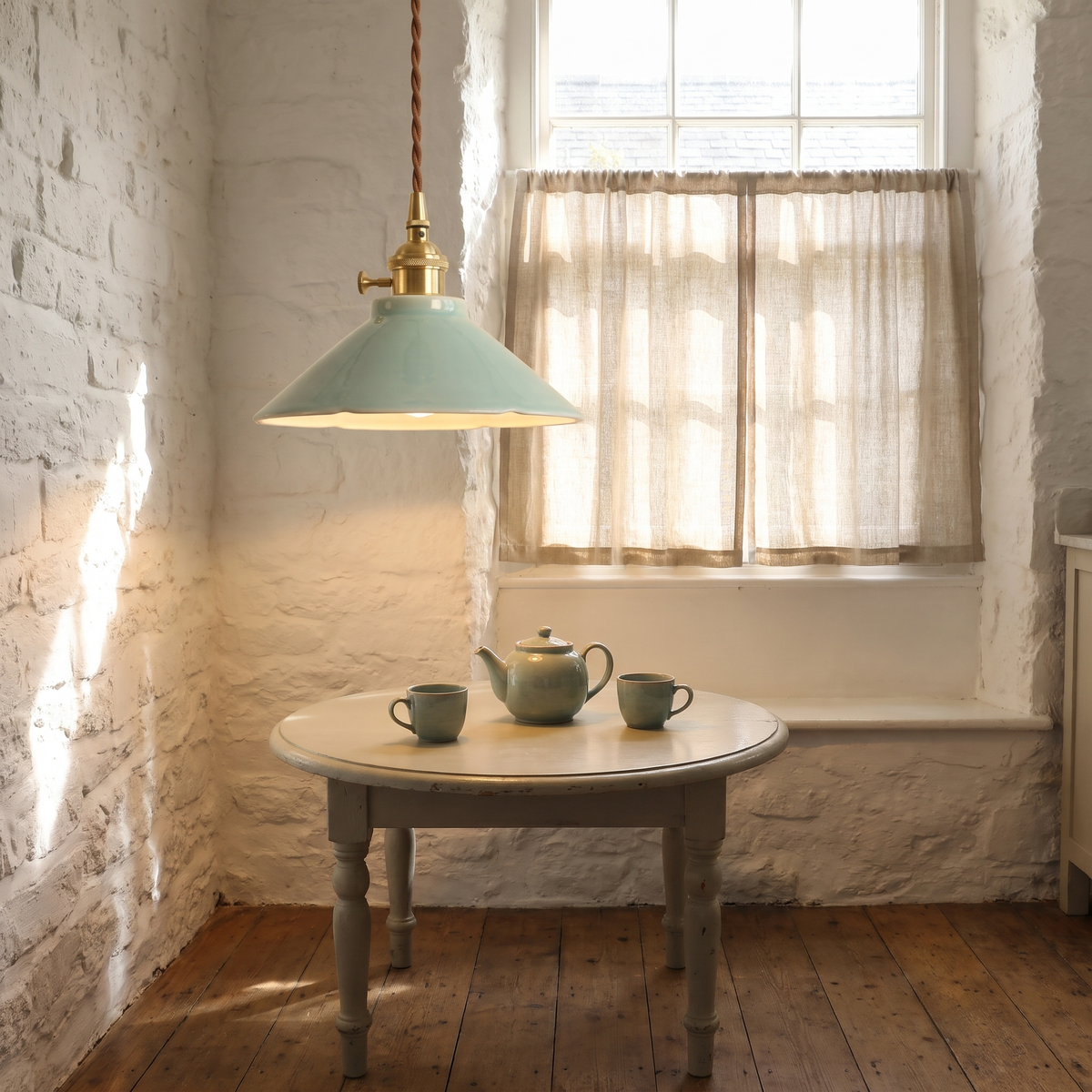 A lit celadon Wortham ceramic pendant light over a small breakfast table