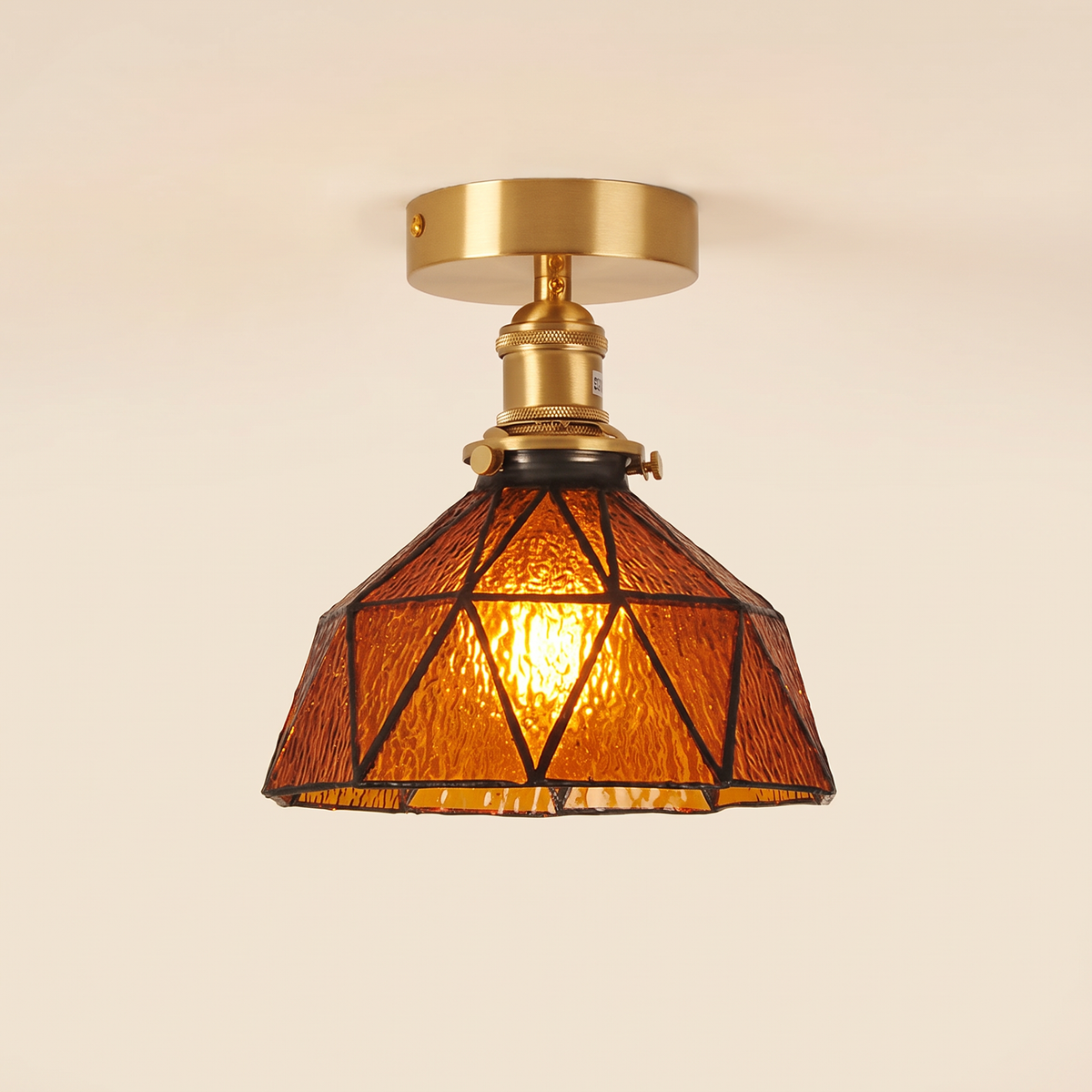Wrentham semi flush ceiling light with a faceted dome of textured amber glass in geometric leading, brass fitting, cream background