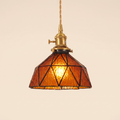 Wrentham pendant light with a faceted dome of textured amber glass in dark geometric leading, brass holder with a turn switch, cream background