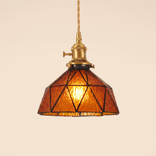 Wrentham pendant light with a faceted dome of textured amber glass in dark geometric leading, brass holder with a turn switch, cream background