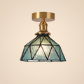 Wrentham semi flush ceiling light with a faceted dome of textured teal glass in geometric leading, brass fitting, cream background
