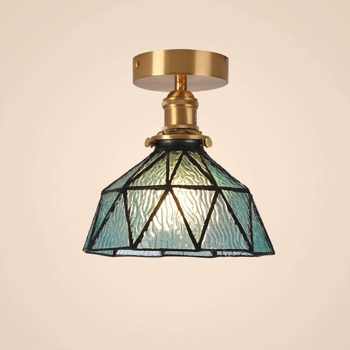 Wrentham semi flush ceiling light with a faceted dome of textured teal glass in geometric leading, brass fitting, cream background
